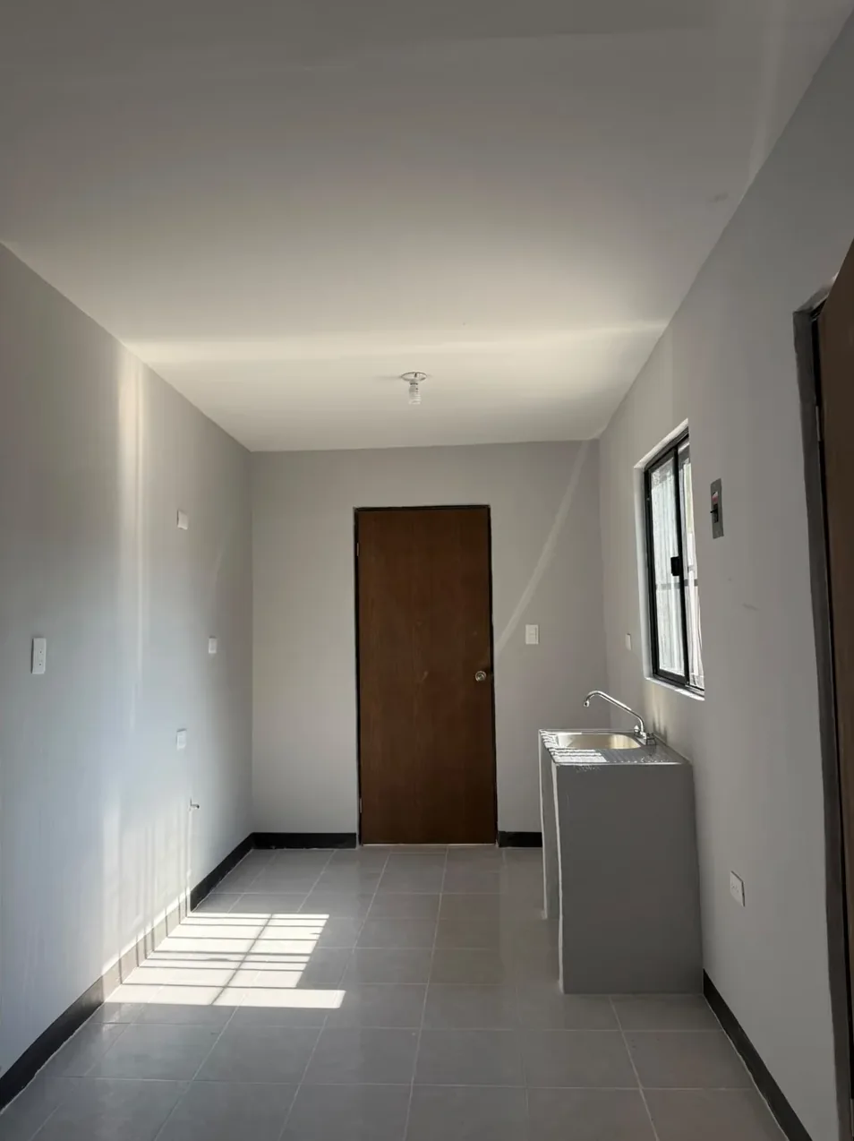 La misma cocina terminada, con muros blancos, tarja y ventana nuevas
