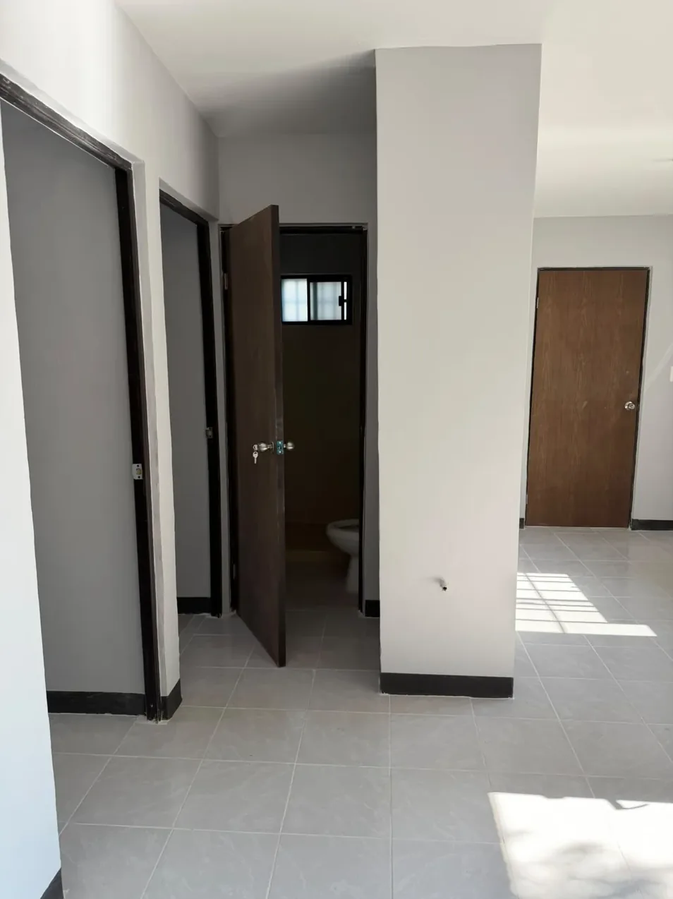 El mismo pasillo terminado, con muros blancos, piso limpio y puertas de madera