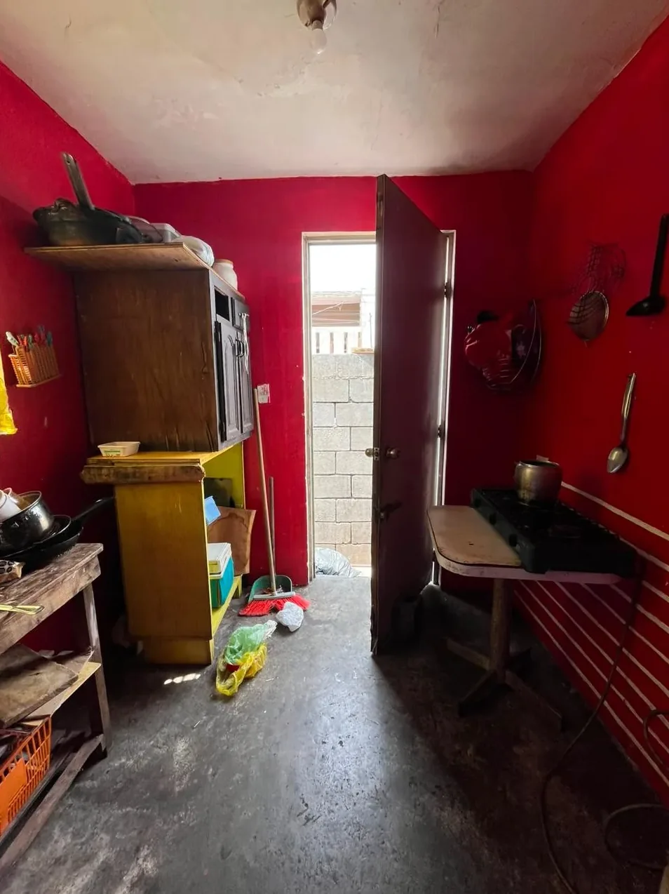 Una cocina en Guadalupe con muros rojos, muebles viejos y cosas por todas partes