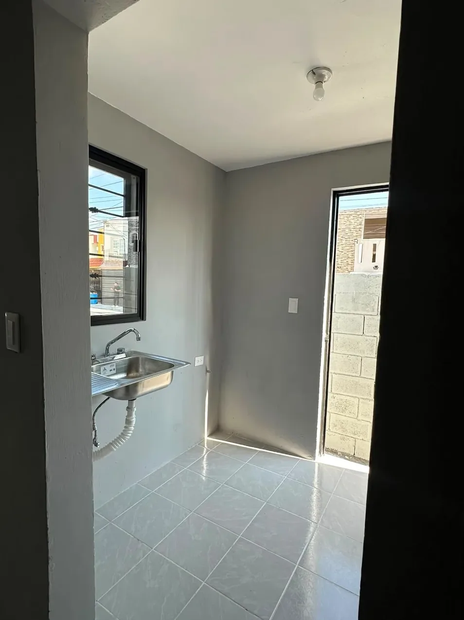 La misma cocina remodelada en gris claro, con tarja y ventana