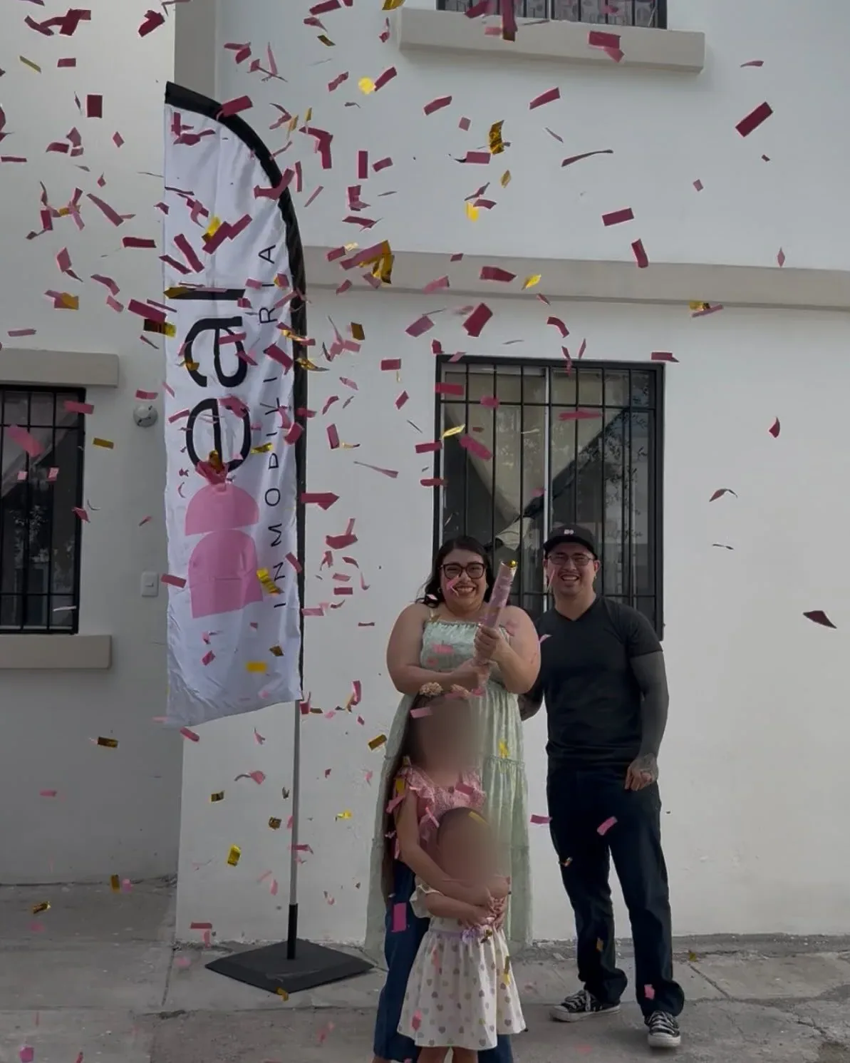 Una familia recibe las llaves de su casa frente a la bandera de Deal, con confeti en el aire